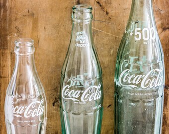 A set of Three (3) Vintage Coca Cola Bottles in three different sizes