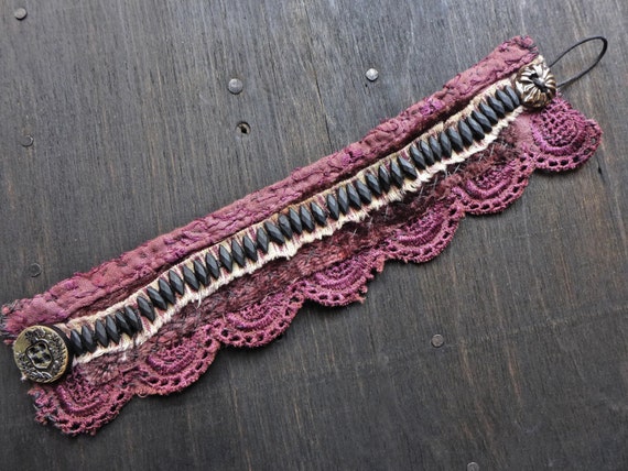 Chthonic. Primitive textile stitched bracelet with antique jet nailheads in plum.