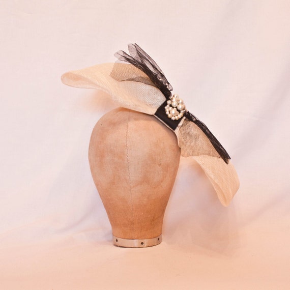 Striking oversized bow shaped cream and black ladies hat with pearl decoration