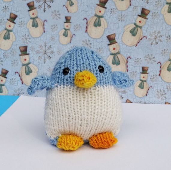 Hand von gestrickter pinguin alpaka spielzeug blaue