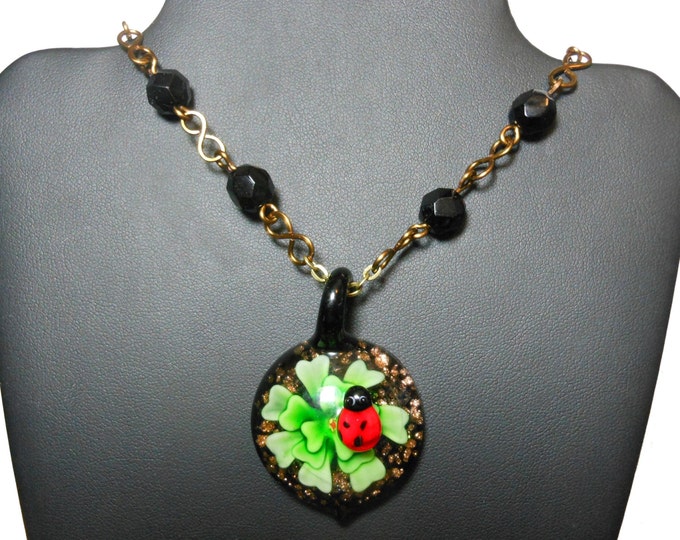 Lampwork ladybug necklace, ladybug on top of a green flower pendant, vintage black wire wrapped faceted glass beads, handmade infinity links