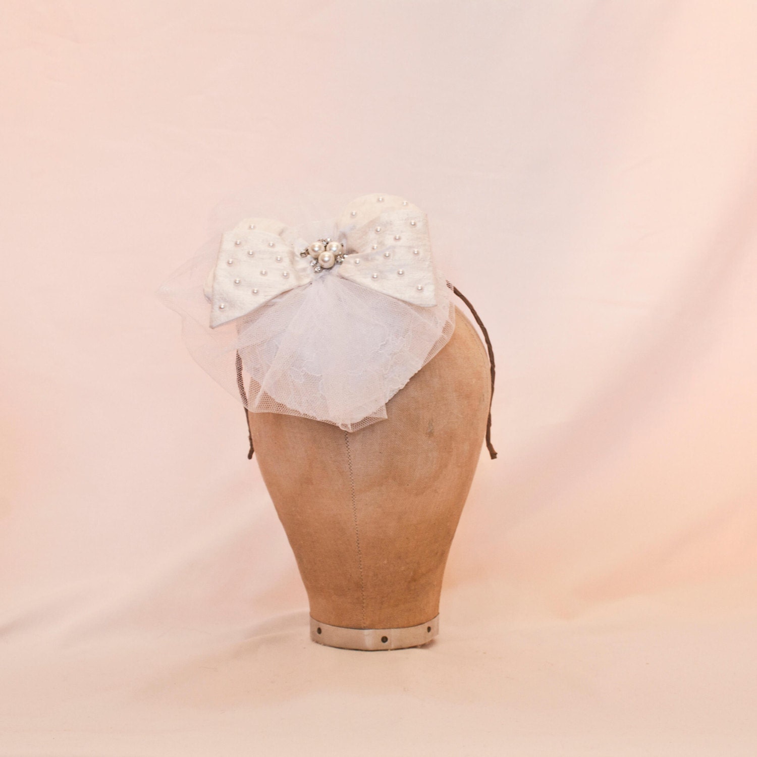 Handmade white heart shaped ladies hat decorated with a small bow and diamanté detailing