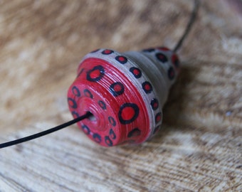 Handgerolde kraal (3x2,5cm) van gerecycled bruin papier met zwart-, en rood stippen design aan zwarte aluminium spang (47cm)