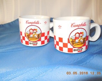 A pair of Campbell's soup mugs with the two Campbell's soup kids on the front.