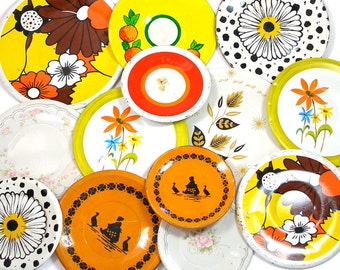 13 Tin Toy tea saucers in yellow, orange, black, 1950s graphics, Instant Collection.