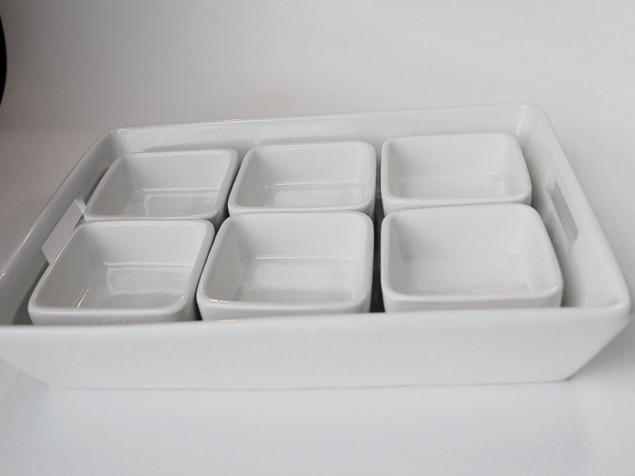 White serving tray with square six square condiment dishes.