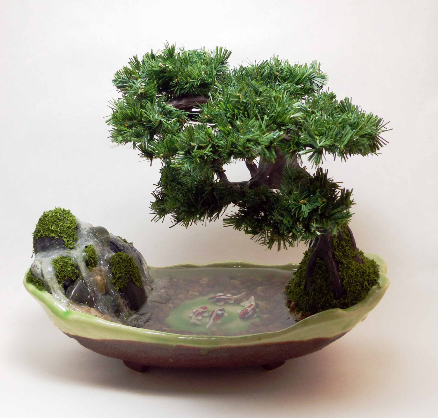 Artificial Koi Pond with waterfall beneath a pine bonsai