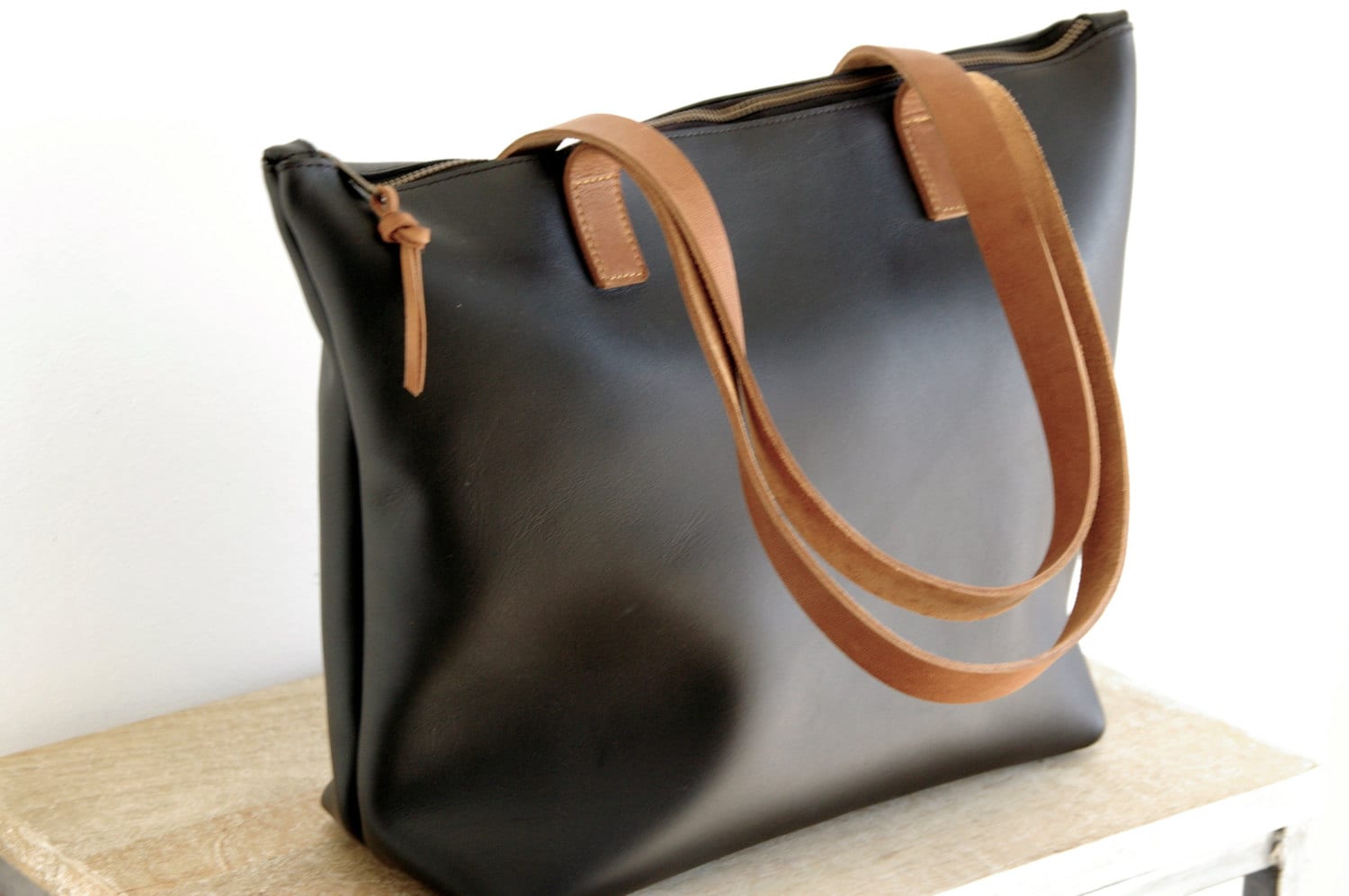 Medium Black Leather bag with zip and brown leather straps.