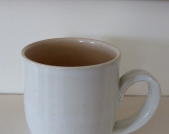 Stoneware mug in creamy white with peach/apricot inside.