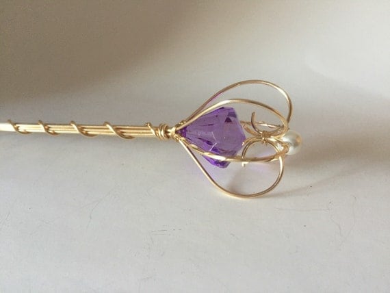 Gold scepter with a purple jewel and pearl