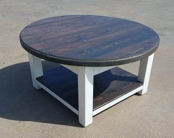 Round farmhouse coffee table with dark walnut stained top and lower shelf, and white distressed skirt and legs. Fixer upper, rustic table
