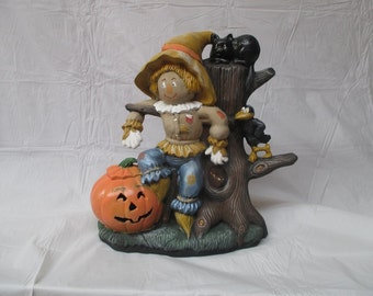 A Scarecrow sitting on a tree stump.