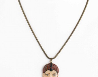 Vintage carved and painted celluloid pendant on 16" brass chain. pdvn804cs(e)