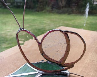 Standing Snail Stained Glass suncatcher on a green leaf