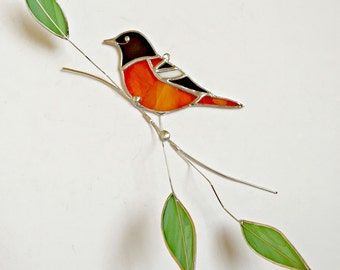 Baltimore Oriole stained glass bird suncatcher on tinned wire branch with green leaves.