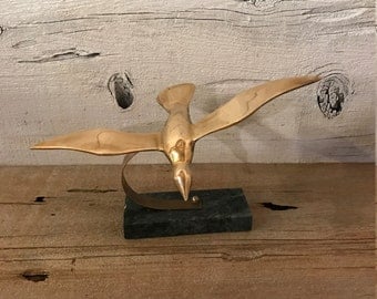 Brass bird on marble stand. Brass flying bird.