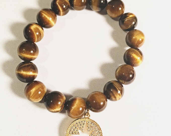 Tigers eye brown 10mm beaded stretch bracelet with a gold crystal rhinestone open starburst disc charm dangling.
