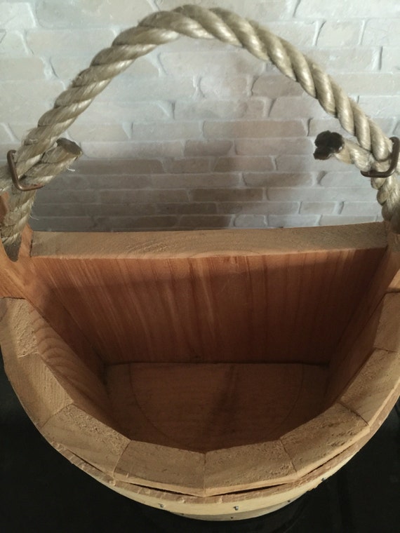 vintage bucket with rope handle. Hangs on wall.