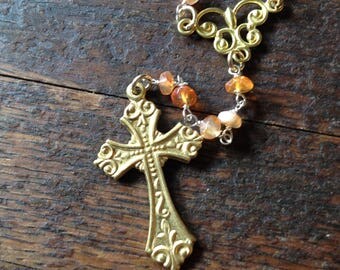 Gold cross rosary necklace. Ornate gold cross necklace with golden swirls for the center piece and orange cornelian beaded rosary chain.