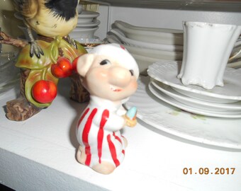 Vintage porcelain pig in night clothes holding a candle figurine