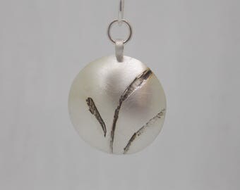 Sterling silver domed disc pendant with etched abstract leaf pattern