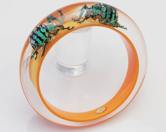 Orange lucite bangle with two glowing real insects