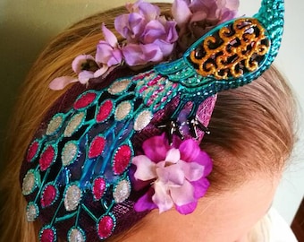 Turquoise peacock fascinator with flower details. Sold, but available with purple peacock.