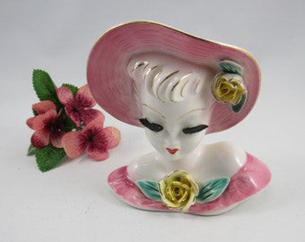 Glamour Girl Lady Head Vase Wall Pocket with Pink Dress,Hat with Flowers and trimmed in Gold. The Vae is 4 1/2" Tall, and made in 1950's