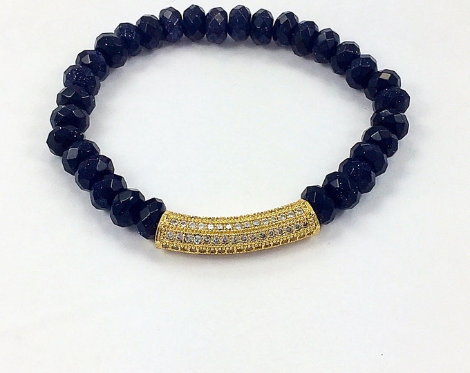 Fashion forward trendsetting style, blue goldstone 8mm beaded bracelet adorned with a pave crystal yellow gold bar.