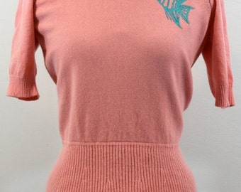 Coral cashmere sweater w/ scoop neckline and gathered waist w/ small skirt. Embroidered with an angel fish design. Originally b