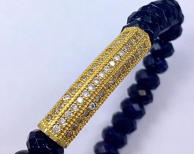 Fashion forward trendsetting style, blue goldstone 8mm beaded bracelet adorned with a pave crystal yellow gold bar.