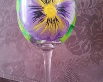 Wine glass hand painted with purple pansies.