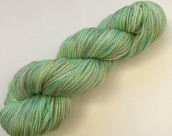 100g skein of luxurious merino and bamboo blend 4ply knitting wool yarn in green with purple, yellow, and blue hand painted spots