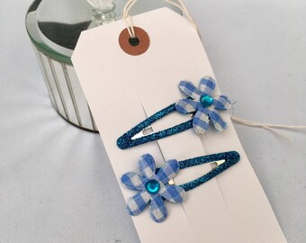 Two blue glitter hair clips with gingham flower detail.