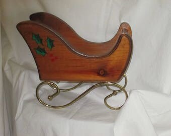 Wooden Santa sleigh, metal curly cue runners, holly leaves and berries as an accent, vintage, natural wood with a natural sealer on sleigh