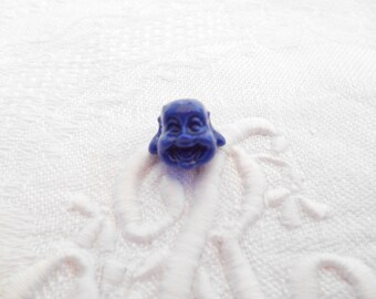 Une perle tête de Bouddha en corail synthétique de couleur bleue marine.