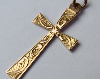 A shaped gold cross with decorative palm leaf etched pattern and hanging loop. The reverse marked 9ct.