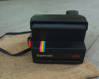 vintage Polaroid Supercolor 600 instant camera, black with camera strip.