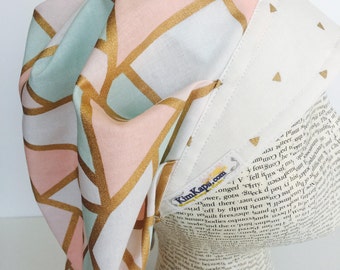Traditional Bouffant Scrub Cap featuring a white material with shapes outlined in gold in pink withe and teal with a coordinating band
