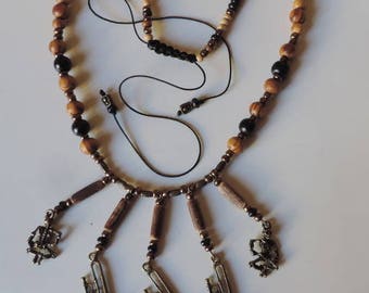 Composition Danse macabre: skeletons and bronze saxophone necklace on wood