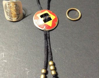 Vintage scarf jewelry, two scarf rings, one silver tone and one gold tone, and one colorful bolo scarf tie.