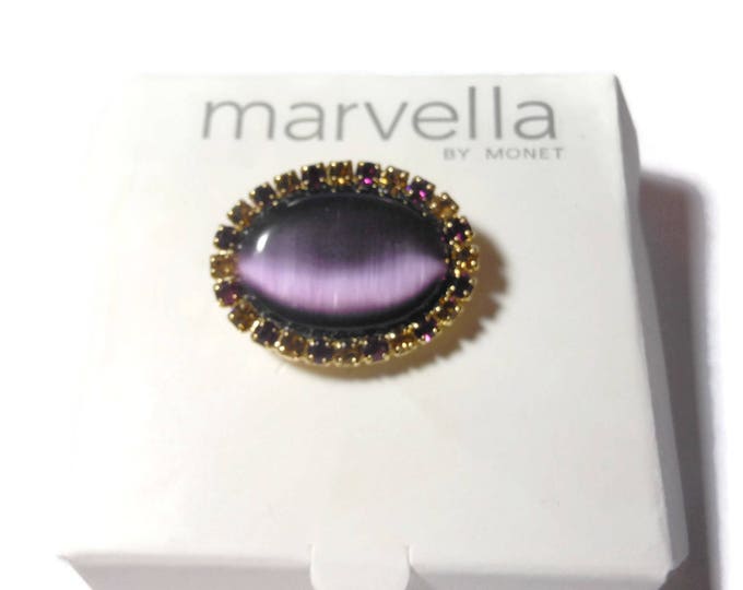 Marvella amethyst cat's eye brooch, Marvella by Monet oval purple glass cabochon surrounded by purple and amethyst frame, gold tone setting