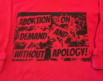 Red prochoice feminist "abortion on demand and without apology" sweater. 20% of sales benefit national network of abortion funds
