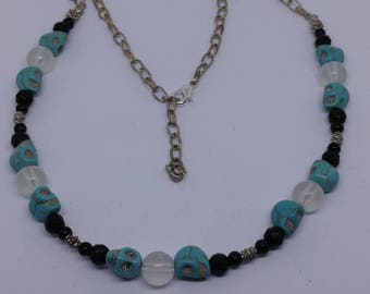 This is a black faceted beaded necklace with turquoise stone skulls and clear glow in the dark glass beads.