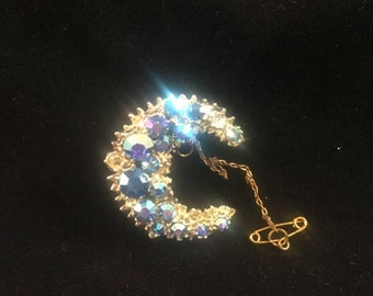 Vintage: Gold present moon brooch with blue diamante detail.