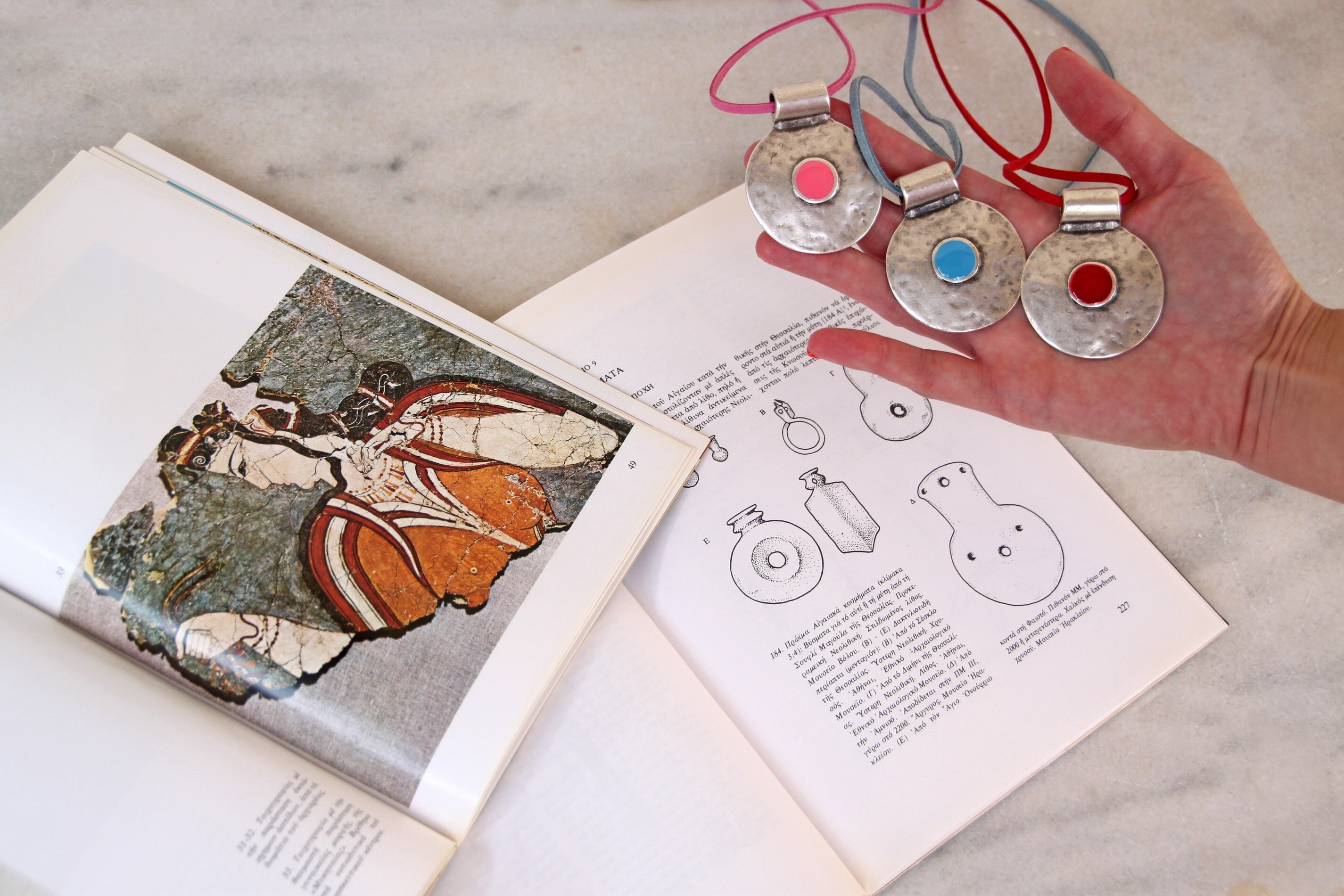 Some of Christine’s pieces feature motifs from ancient art, such as fish bones. Others resemble ancient Greek pendants with a twist of xroma flair: a dash of bold resin at the center