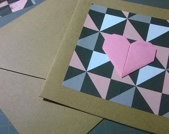 Carte origami, coeur rose sur fond géometrique