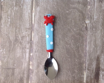 child spoon decorated with a red crab made with fimo