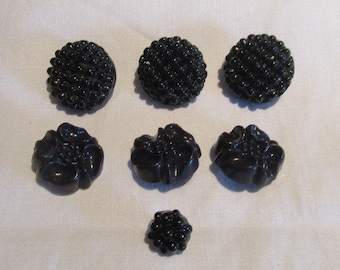 Riveted black glass mirror back buttons x 2; moulded floral navy celluloid buttons x 3; 2 extra black riveted buttons; Edwardian