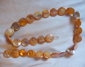 Bead, Mother of Pearl, 15mm Flat Round Coin, Shades of Orange, Very Shiny. Sold per 15 inch strand. There are 29 beads on the strand.